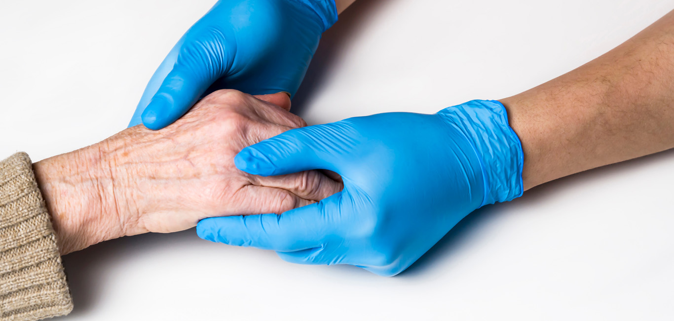 gloved hands holding palm of parkinson patient