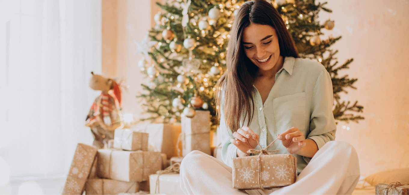 Woman opening gifts during the Christmas, with a Christmas tree in the background