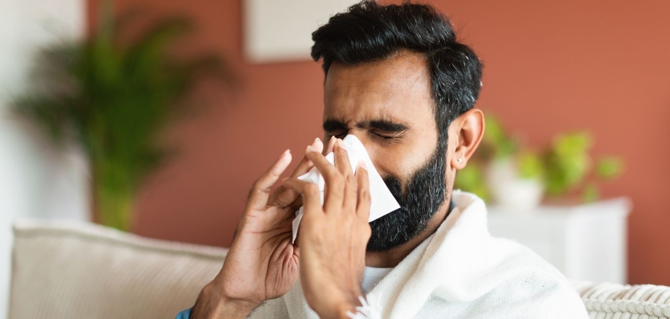 An image of a man holding a tissue to his nose